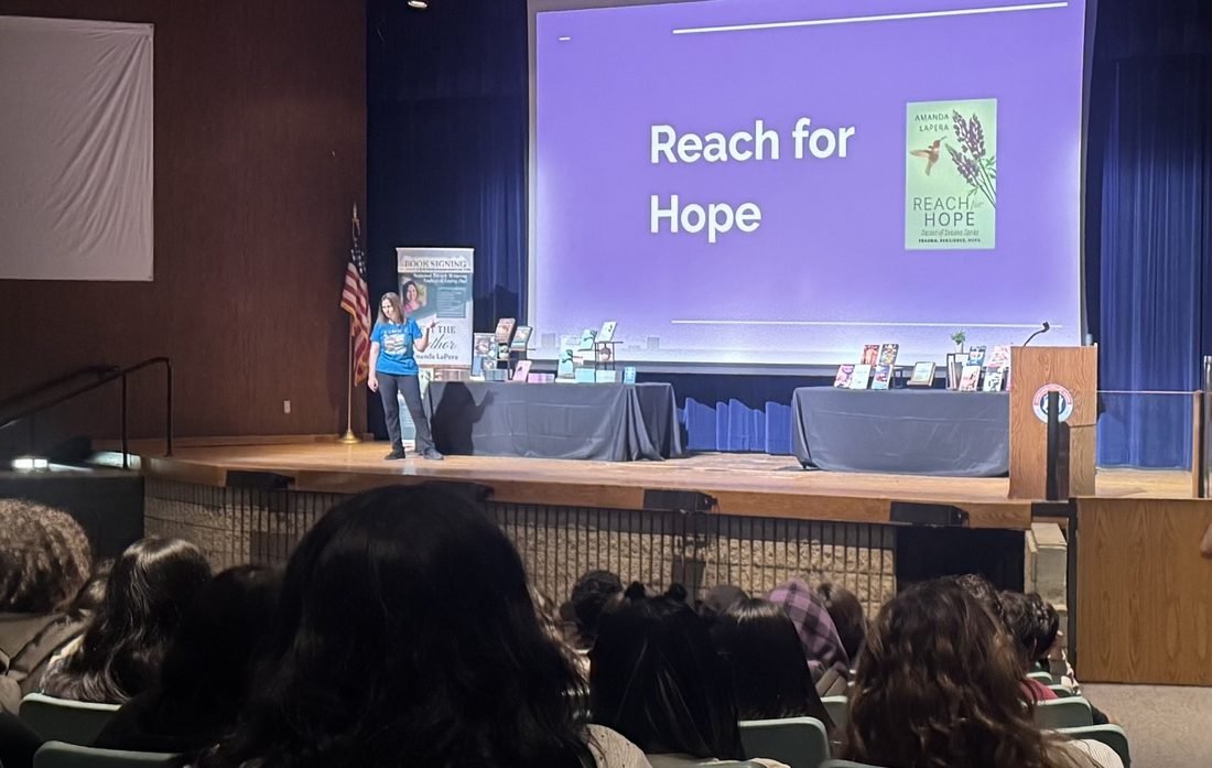 Amanda LaPera presenting on stage to a large audience.